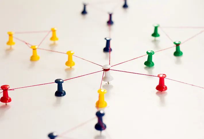 Pins auf weißer Oberfläche, die mit einem roten Faden verbunden sind